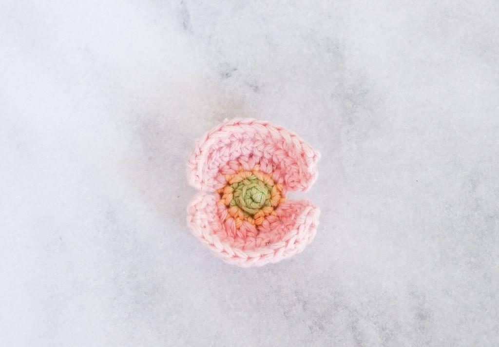 Pink crochet poppy flower with a green centre