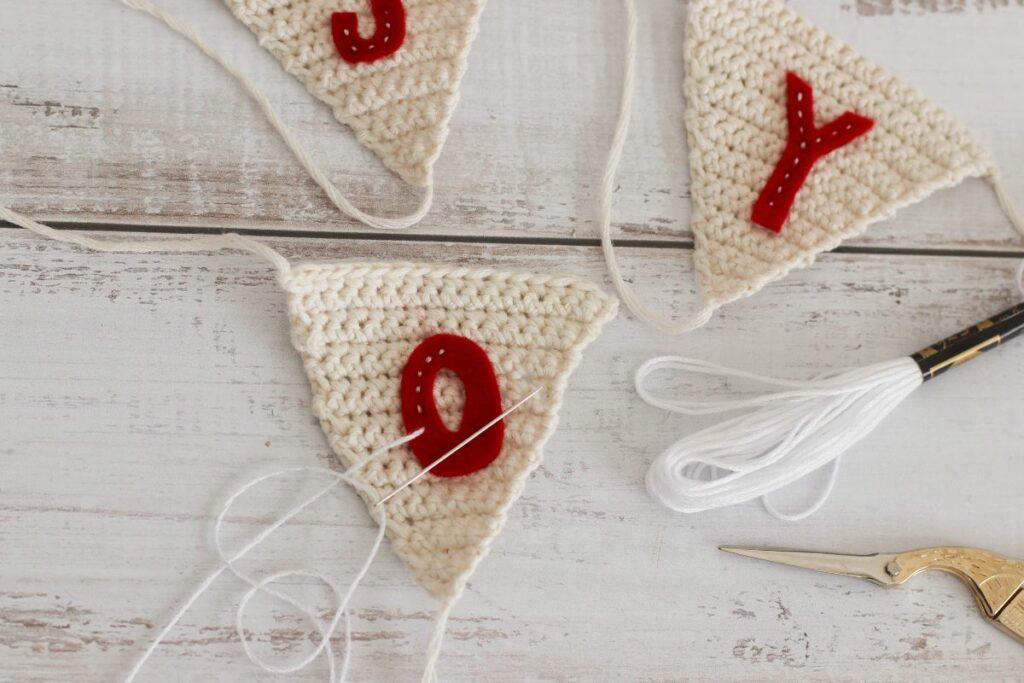 stitching red letters onto crochet bunting garland 