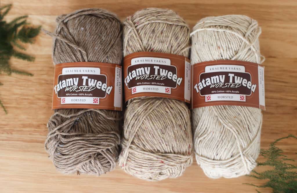 three skeins of yarn (Tatamy Tweed Worsted yarn) in neutral colors on a wooden background.