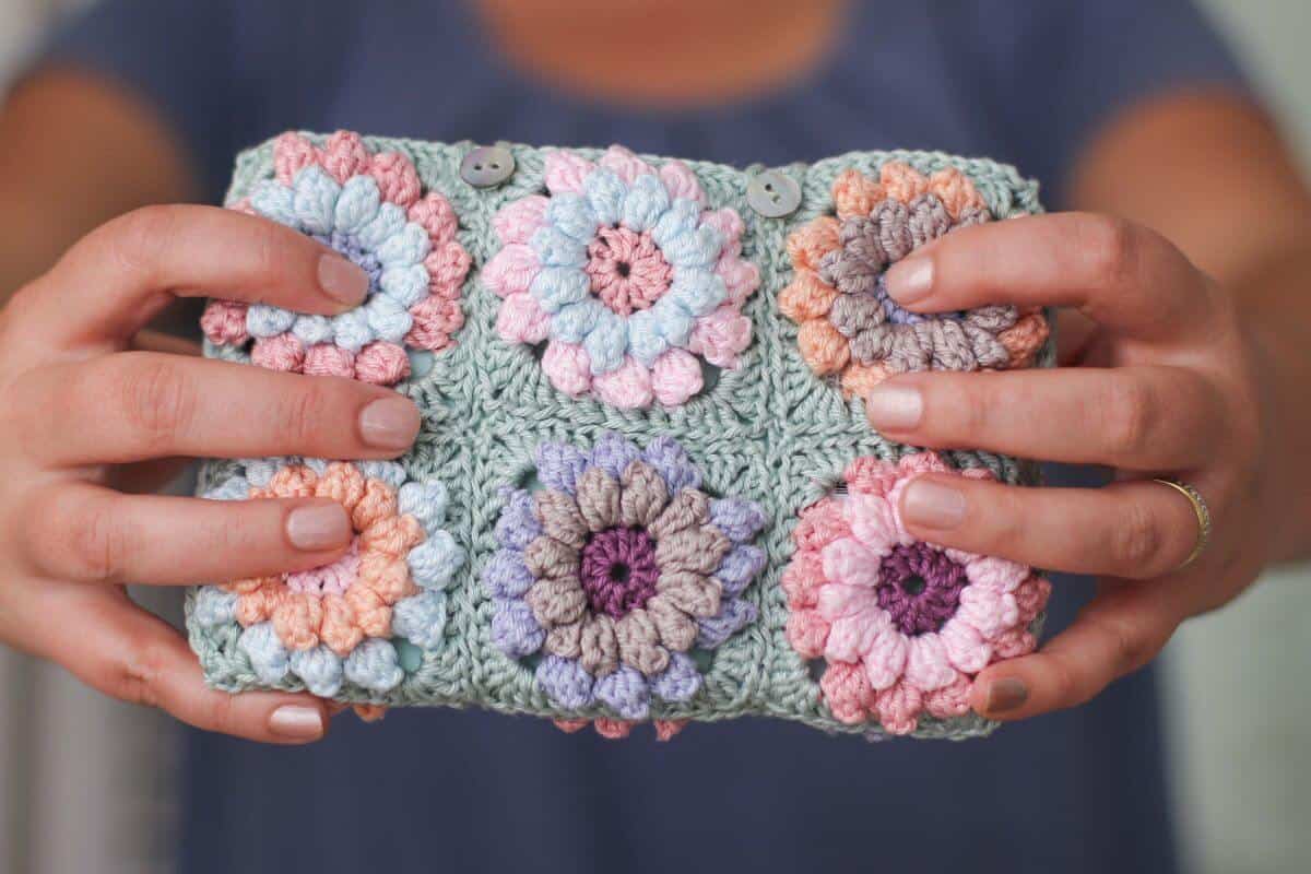 Woman holding a completed crochet flower clutch bag