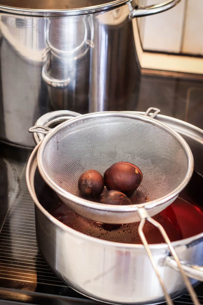 making avocado dye on the stove top, avocado pits in a strainer