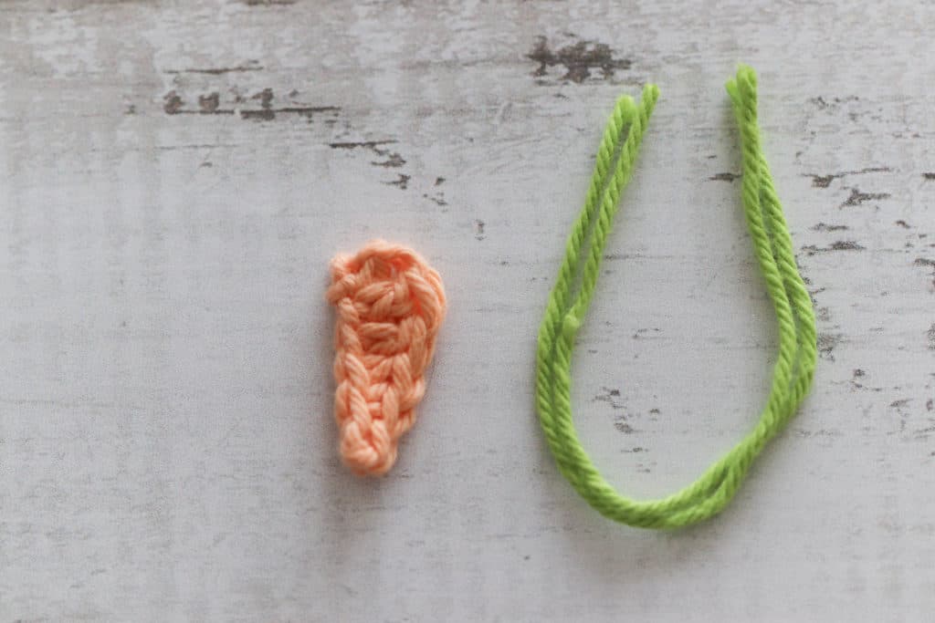 orange crochet carrot next to some green yarn