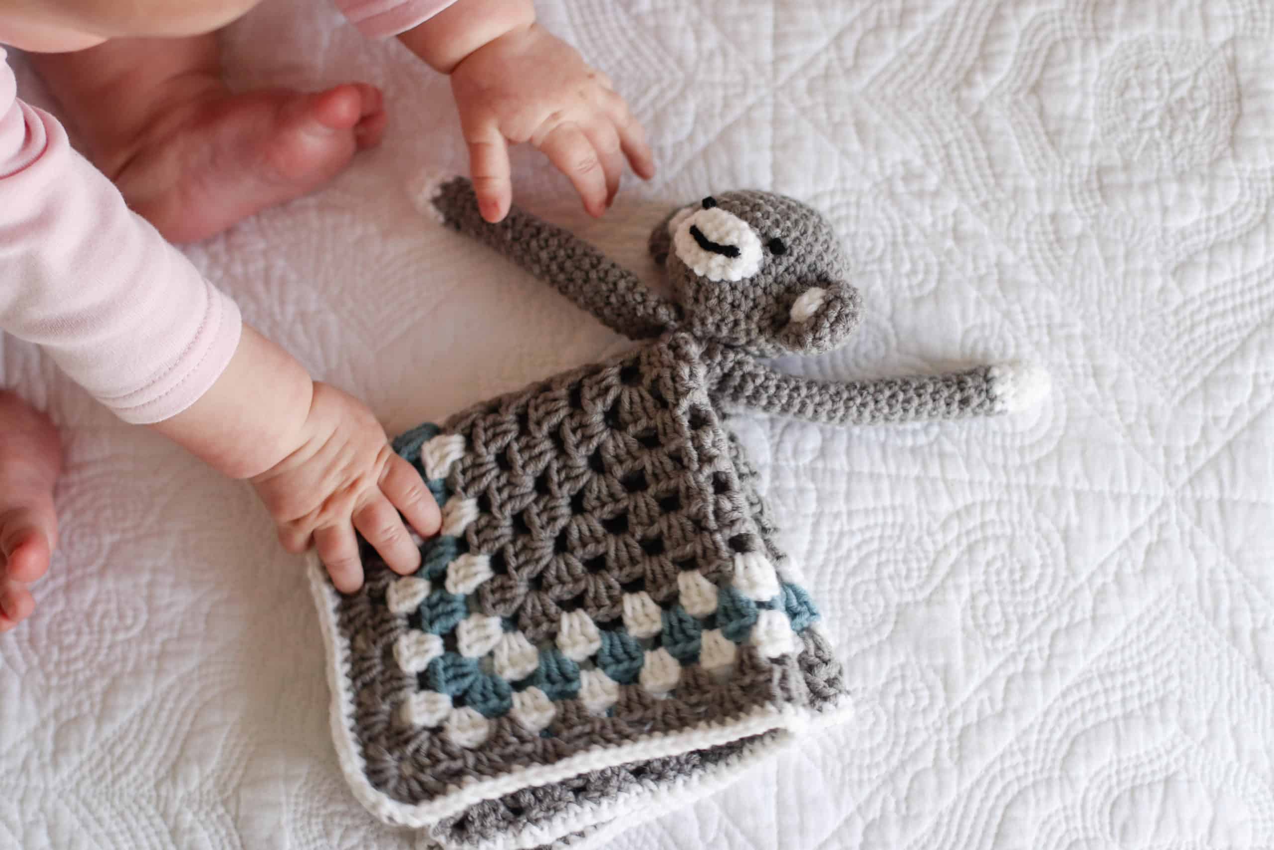 baby playing with crochet monkey security blanket