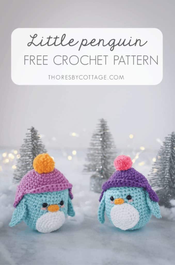 two blue crocheted penguins from this free crochet penguin pattern in a cold winter scene with glittery trees in the background