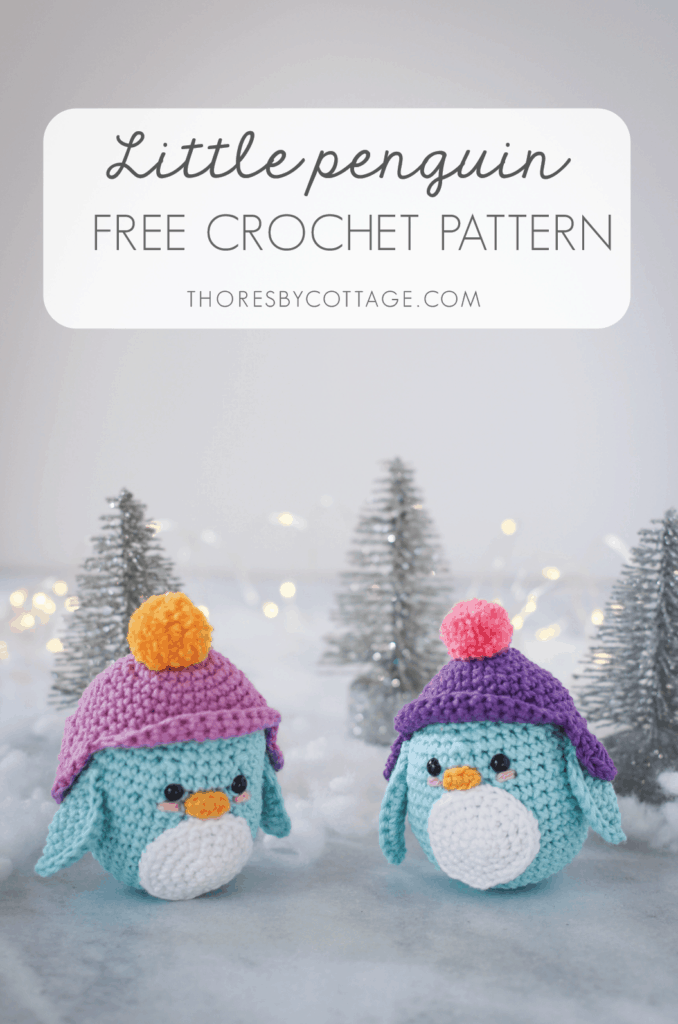 two blue crocheted penguins in a cold winter scene with glittery trees in the background