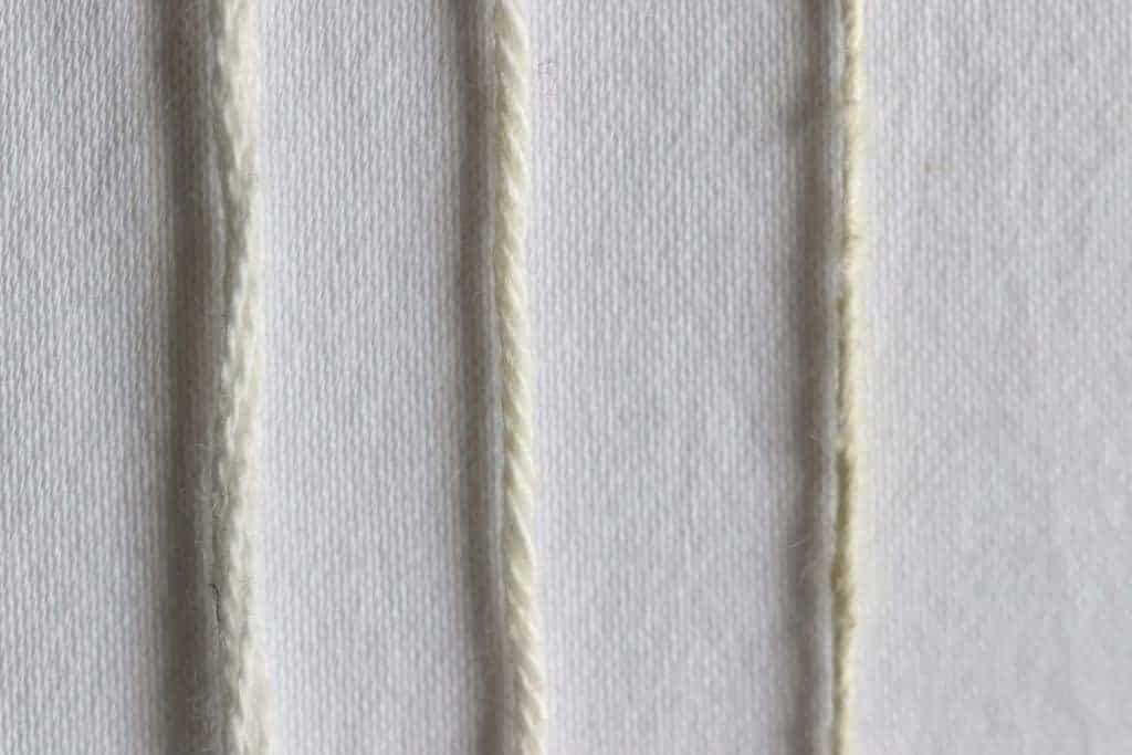 Cream colored yarns showing different yarn plies. 3 ply yarn vs 2 ply yarn vs single.