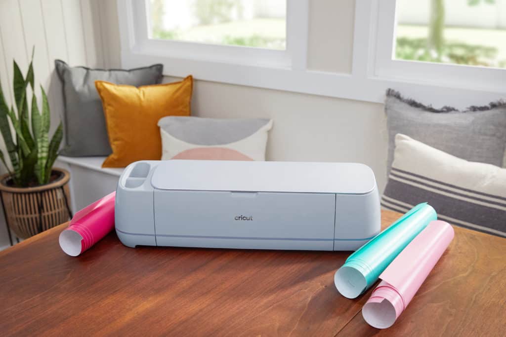 Cricut machine surrounded by rolls of colorful vinyl