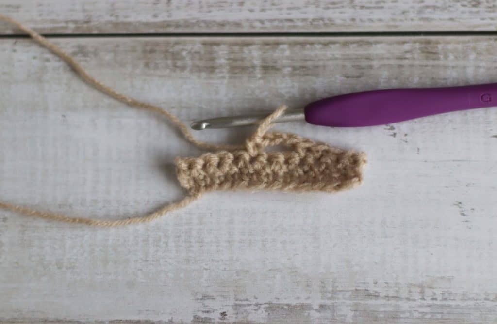 piece of crochet and a purple crochet hook