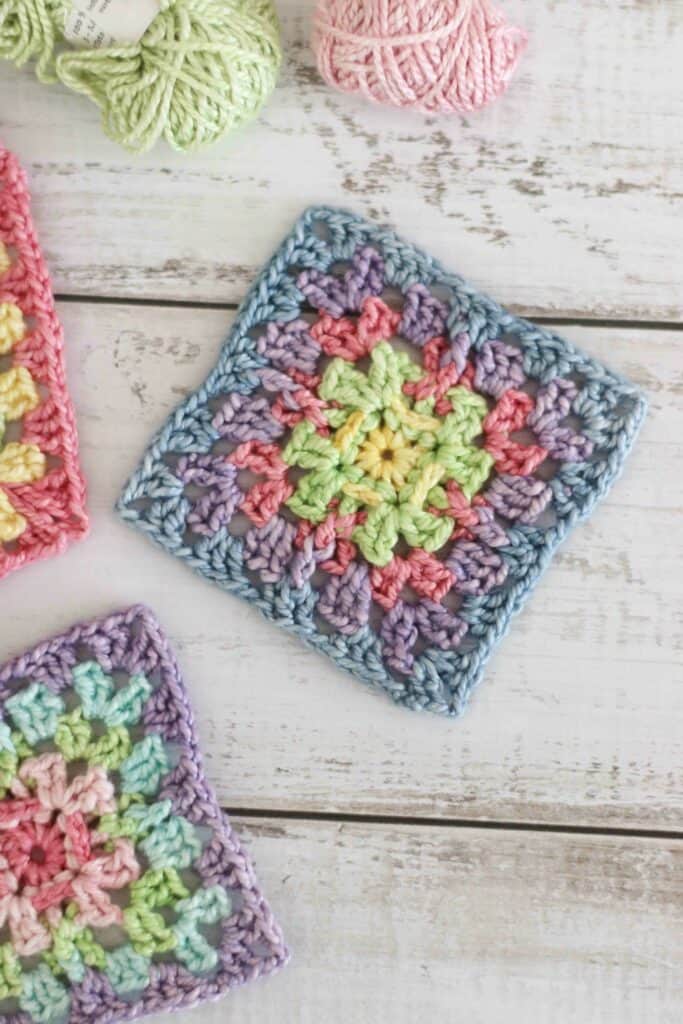 Granny square crochet pattern for a modern crochet square - rainbow coloured crochet square on a wooden texture background.