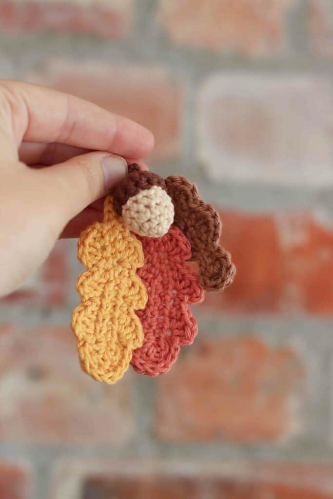 autumn crochet pattern | crochet oak leaves in yellow, orange and brown, held together with a little crochet acorn