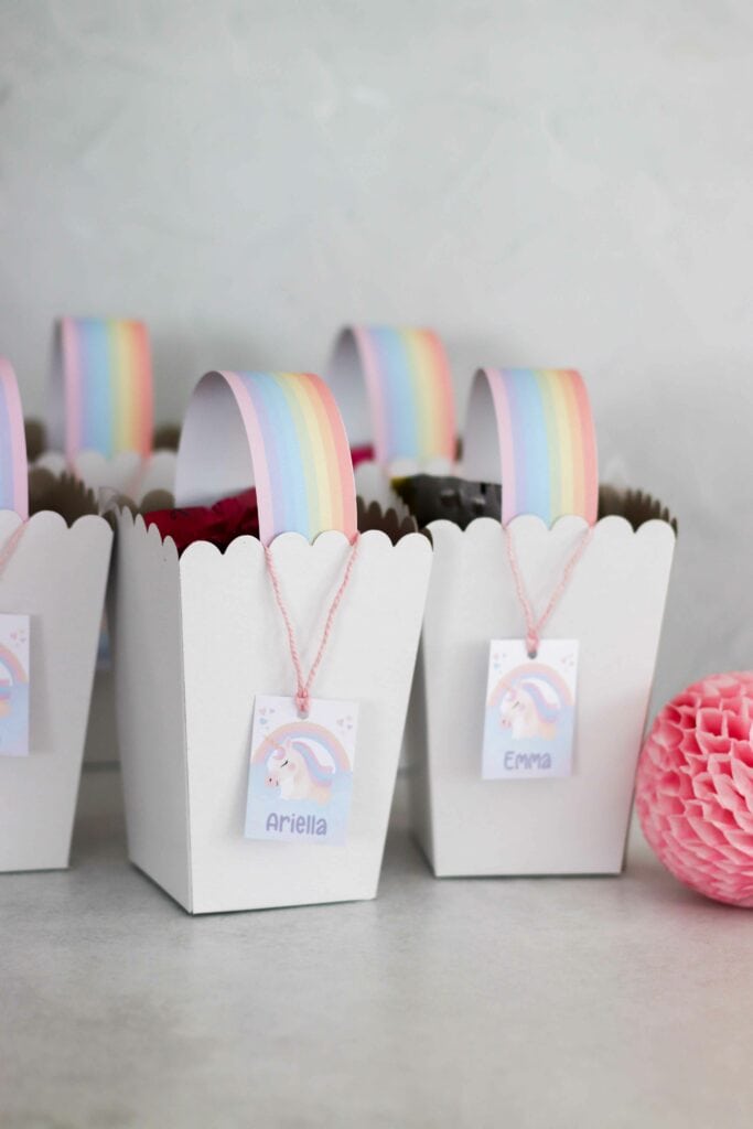 DIY rainbow party favor gift bags | Cardboard popcorn box with a rainbow handle and unicorn name label