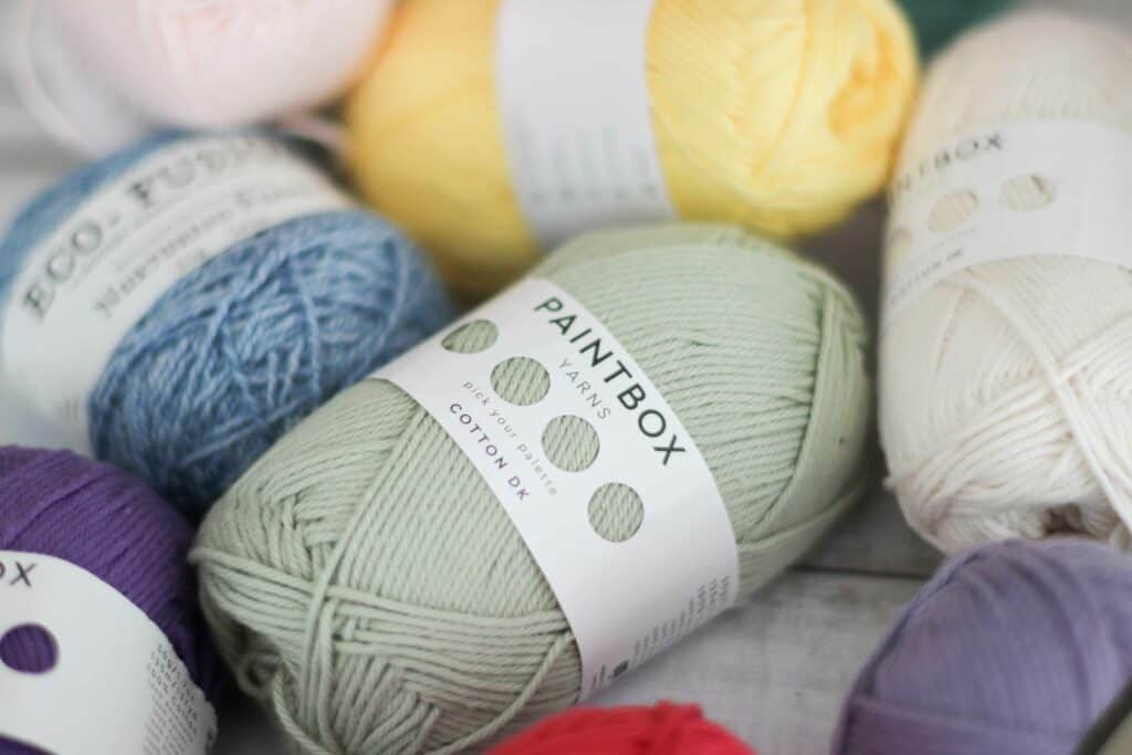 Balls of yarn of different colors held together with a yarn ball band | Paint box yarns cotton DK in the color Pistachio
