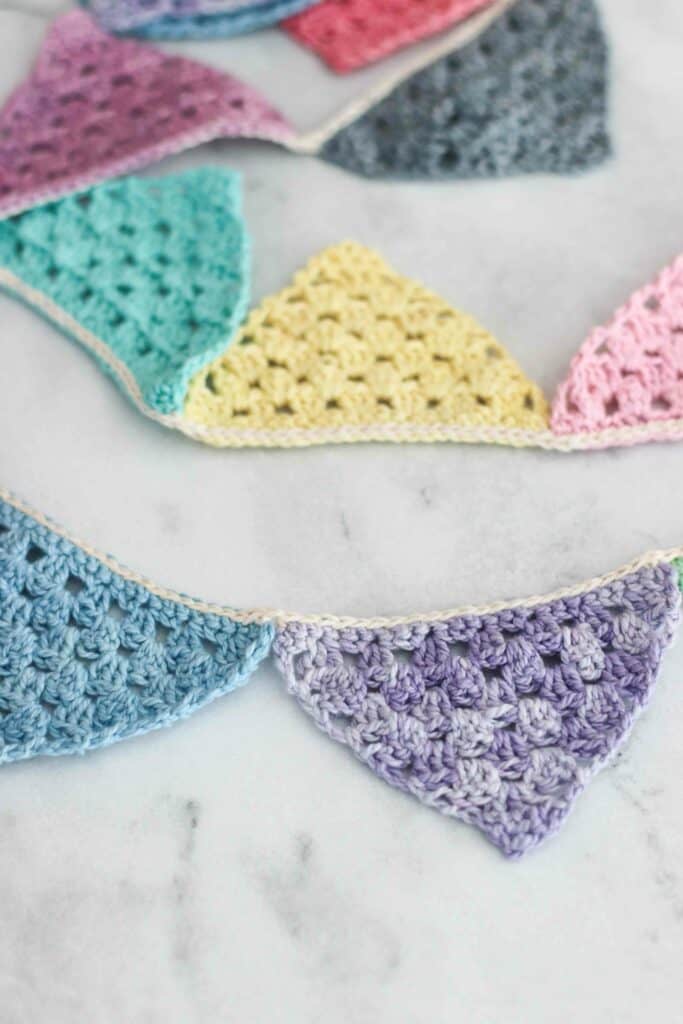 close up the finished item made from the crochet bunting pattern | macaron colored crochet triangles joined together as bunting