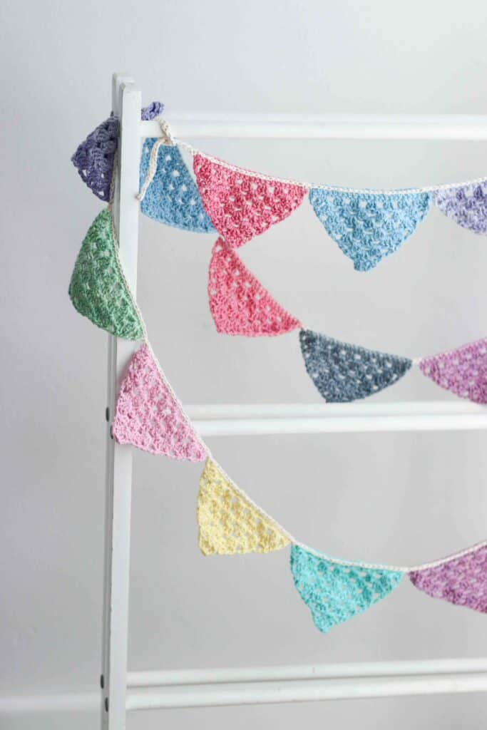 Brightly colored crochet bunting hanging on a wooden stand