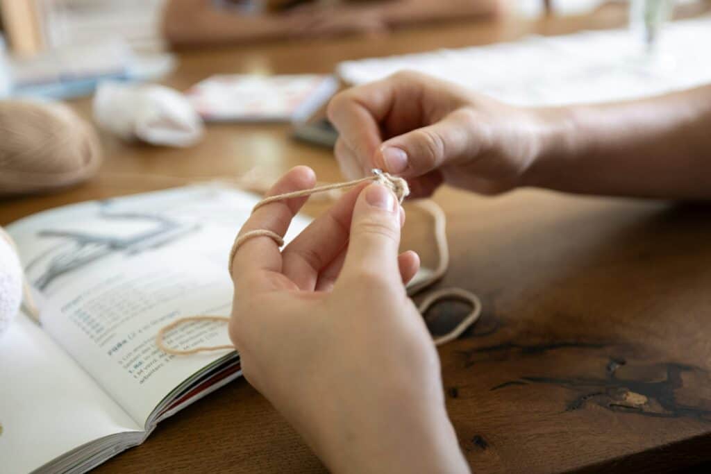 Selling crochet patterns on Etsy: Pros and Cons Hands working on a handmade crocheted project, following a crochet pattern. Pros and cons of selling crochet patterns on Etsy.